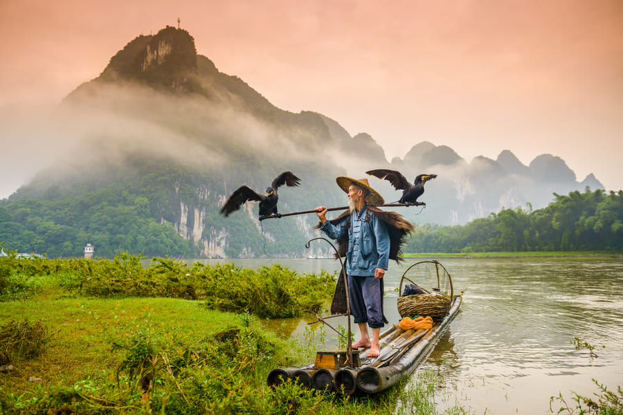 pescador en una lancha, en una laguna de china en las montañas